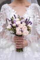 Hands of the bride close-up with a bouquet of fresh beautiful flowers. Attribute of the bride photo