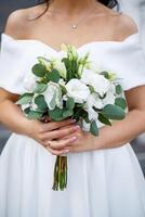 Hands of the bride close-up with a bouquet of fresh beautiful flowers. Attribute of the bride photo