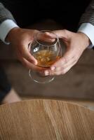 A man businessman holds a glass with alcohol in his hand. Dressed in a jacket and shirt. Rest after a working day photo