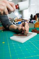 The hands of the master sew handmade leather products. Men's hands connect the parts, creating quality leather accessories. Working process in a leather workshop photo