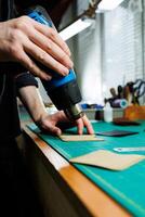 The hands of the master sew handmade leather products. Men's hands connect the parts, creating quality leather accessories. Working process in a leather workshop photo