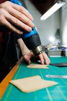 The hands of the master sew handmade leather products. Men's hands connect the parts, creating quality leather accessories. Working process in a leather workshop photo