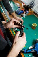 The hands of the master sew handmade leather products. Men's hands connect the parts, creating quality leather accessories. Working process in a leather workshop photo