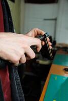 The hands of the master sew handmade leather products. Men's hands connect the parts, creating quality leather accessories. Working process in a leather workshop photo