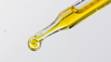 A Drop of Golden Liquid Hanging From A Dropper photo