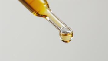 A Single Drop of Golden Elixir Hanging From a Dropper photo