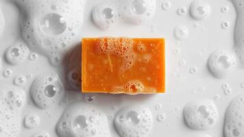 A Single Bar of Orange Soap Lathers Up in a Basin of Bubbly Water photo