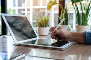 A man using a pen to write on a laptop photo
