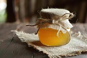 Honey jar with jute bag on wooden table photo