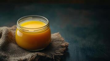 Homemade ghee displayed in a container against a dark background. photo