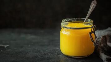 Dark background container holding homemade ghee. photo