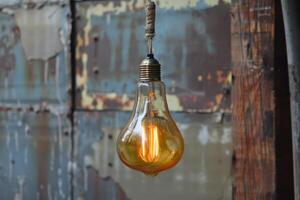 A light bulb hanging from a rope on a rusty wall photo