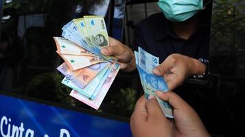 A man wearing a face mask is handing money to another man photo