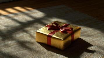 A Golden Gift Box with Red Ribbon on a Textured Surface photo