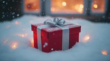 Red Gift Box with Silver Bow Covered in Snow photo
