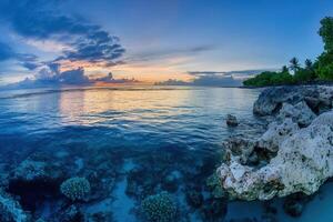 Serene coastal sunset over calm waters and coral. photo