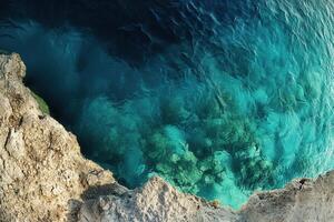 Aerial view of clear turquoise water and rocky shoreline. photo