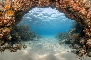Underwater scene showcasing a coral arch and sandy floor. photo