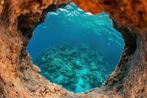 Underwater view of coral reef through a rocky opening. photo