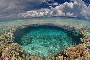 Vibrant coral reef with clear turquoise waters and clouds. photo