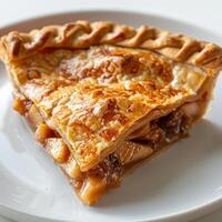 A slice of apple pie with visible pastry crust, topped with a baked apple and caramel sauce. photo