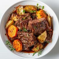 A bowl of beef and vegetable stew, featuring meat on the bone, potatoes, carrots, parsley, photo