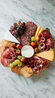 A platter of meat, cheese, fruit and crackers photo