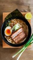 A bowl of ramen with meat, eggs and a slice of lime photo