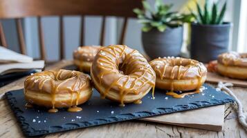 Three donuts with caramel drizzle on top on a black slate photo
