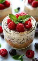 A jar of dessert with raspberries and mint leaves on top. The dessert is a combination of chocolate and raspberry flavors photo