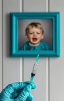 Child's fear showcases vaccination moment. A hand holds a syringe in front of a framed photo of a crying child, illustrating vaccination anxiety.