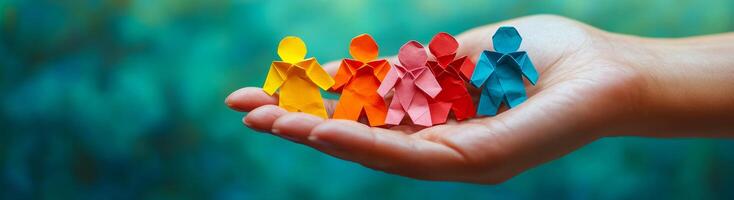 A hand holding a stack of colorful paper cutouts of people. The people are of different colors and sizes, and they are arranged in a row. Concept of unity and togetherness photo