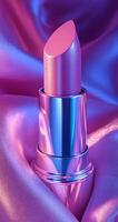 A pink lipstick is shown on a purple background. The lipstick is shiny and has a metallic finish. The image has a dreamy, ethereal quality to it, with the lipstick appearing almost like a work of art photo