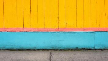 A yellow and blue wall with a red stripe. The wall is painted in a way that it looks like a fence photo