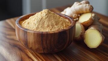 Fresh ginger root and ground ginger in wooden bowl. Ground ginger sits in a wooden bowl next to fresh ginger root on a rustic wooden surface in natural light. photo