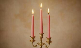 Three pink candles are lit and sitting on a gold candlestick photo