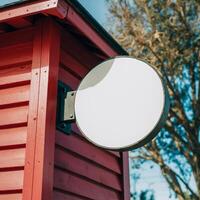 Red wooden structure with blank circular signboard, tree and clear sky background For Social Media Post Size photo