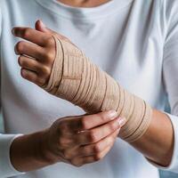 Wrist wrapped in beige bandage, person adjusting it, white top visible For Social Media Post Size photo