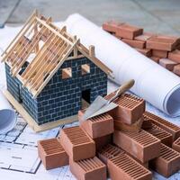 Construction site features wooden framework house, bricks, blueprints, and trowel For Social Media Post Size photo