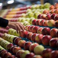 Hand reaches to pick red apple from a neatly arranged display of fresh fruit For Social Media Post Size photo