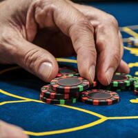 Hand placing colorful poker chips on blue table, with visible wrinkles and markings For Social Media Post Size photo