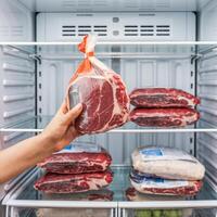Hand holds plastic wrapped meat in fridge, similar packages on glass shelves For Social Media Post Size photo