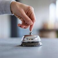 Hand about to ring shiny metallic bell, with a calm, focused indoor background For Social Media Post Size photo