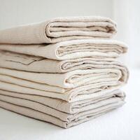 Stack of light beige cloths with soft texture, neatly arranged, slightly overlapping, white background For Social Media Post Size photo