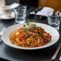 Plate of noodles with vegetables and meat, restaurant setting implied For Social Media Post Size photo