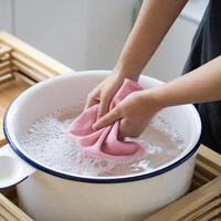 Hands wring cloth in soapy basin on wood surface, suggesting cleanliness For Social Media Post Size photo