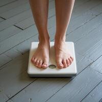 Bare feet on weighing scale, gray floor, partial view of legs For Social Media Post Size photo