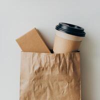 Brown paper bag with coffee cup, box inside on white background emphasizes simplicity For Social Media Post Size photo