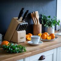 Tidy kitchen countertop with oranges, knife block, herbs, and a dark backdrop For Social Media Post Size photo
