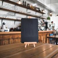 Wooden table holds empty chalkboard menu in cozy cafe, blurred background For Social Media Post Size photo